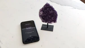 Crystal Cleanse app showing an amethyst session at 1:22, next to an amethyst cluster on a stand