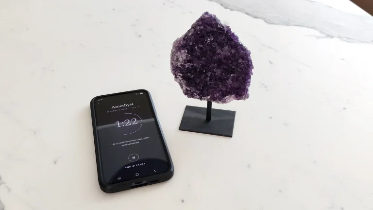 Crystal Cleanse app showing an amethyst session at 1:22, next to an amethyst cluster on a stand
