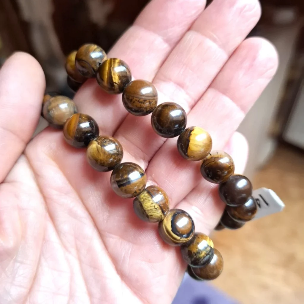 Tiger’s eye bracelet with polished golden-brown beads resting in an open palm.